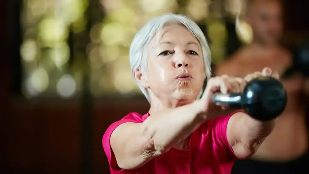 Older woman doing weight training Chigwell to help her strength and longevity 
