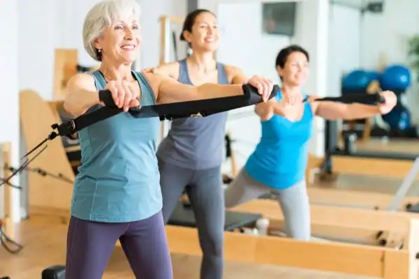Toning Arms After 60: Empowering Womens Fitness Through Effective Weight Training 2 older woman doing weight training Chigwell and resistance in the gym to tone upper arms