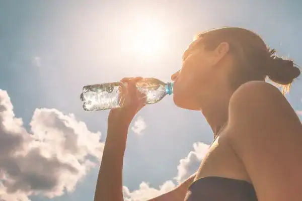 Hydration: The Secret Ingredient for a Toned Stomach and Enhanced Fitness 3 Image of woman drinking water to hydrate Chigwell after run.