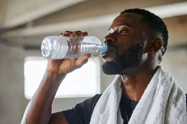 Image of man drinking water to improve hydration Chigwell after work out.